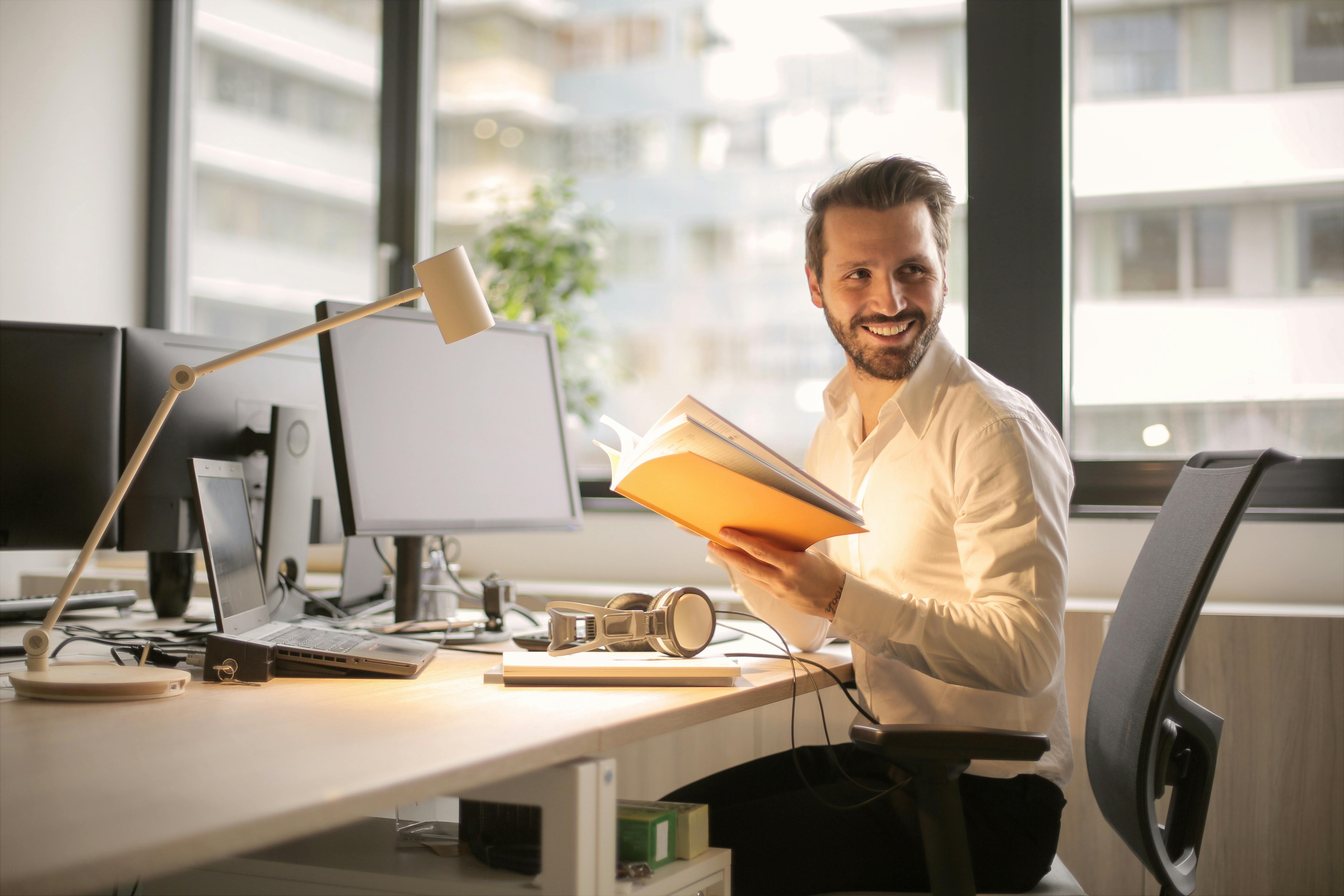 a man sitting with a book in hand and smiling